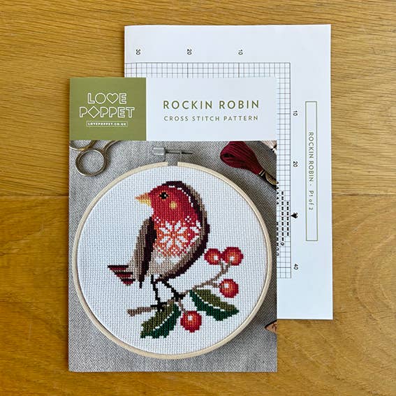 Cross stitch kit with a completed design of a robin bird on a wooden surface