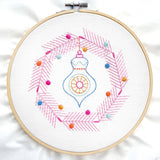 Embroidery hoop with colorful embroidered design on a white background