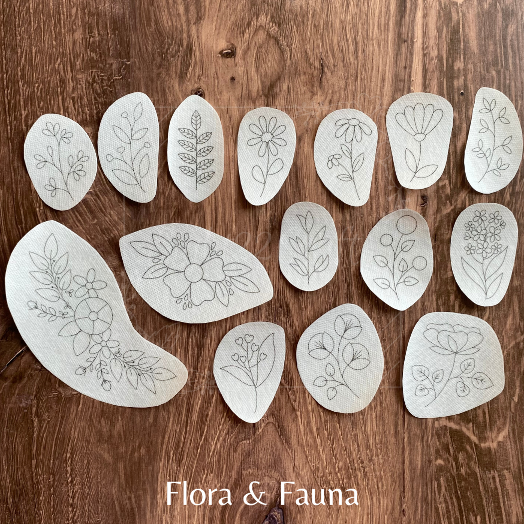 Set of white stencils with floral and leaf designs on a wooden surface, branded 'Flora & Fauna'.