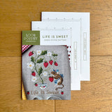 Cross stitch pattern with a mouse and strawberry design on a wooden surface