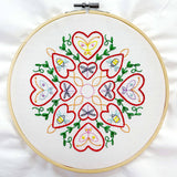 Embroidery hoop with a colorful heart and butterfly design on a white background