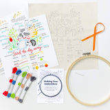 Embroidery kit with pattern sheets, threads, and an embroidery hoop on a white background