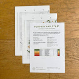 Cross stitch pattern sheets for 'Pumpkin and Stars' on a wooden surface