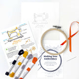 Embroidery kit with hoop, threads, and guide on a white background