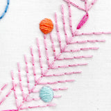 Embroidery with pink leaves and colorful beads on a white background