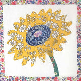 Decorative quilt with a yellow sunflower design on a floral border