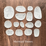 Set of ocean-themed stamps on a wooden surface with 'Mermaid Shores' branding.