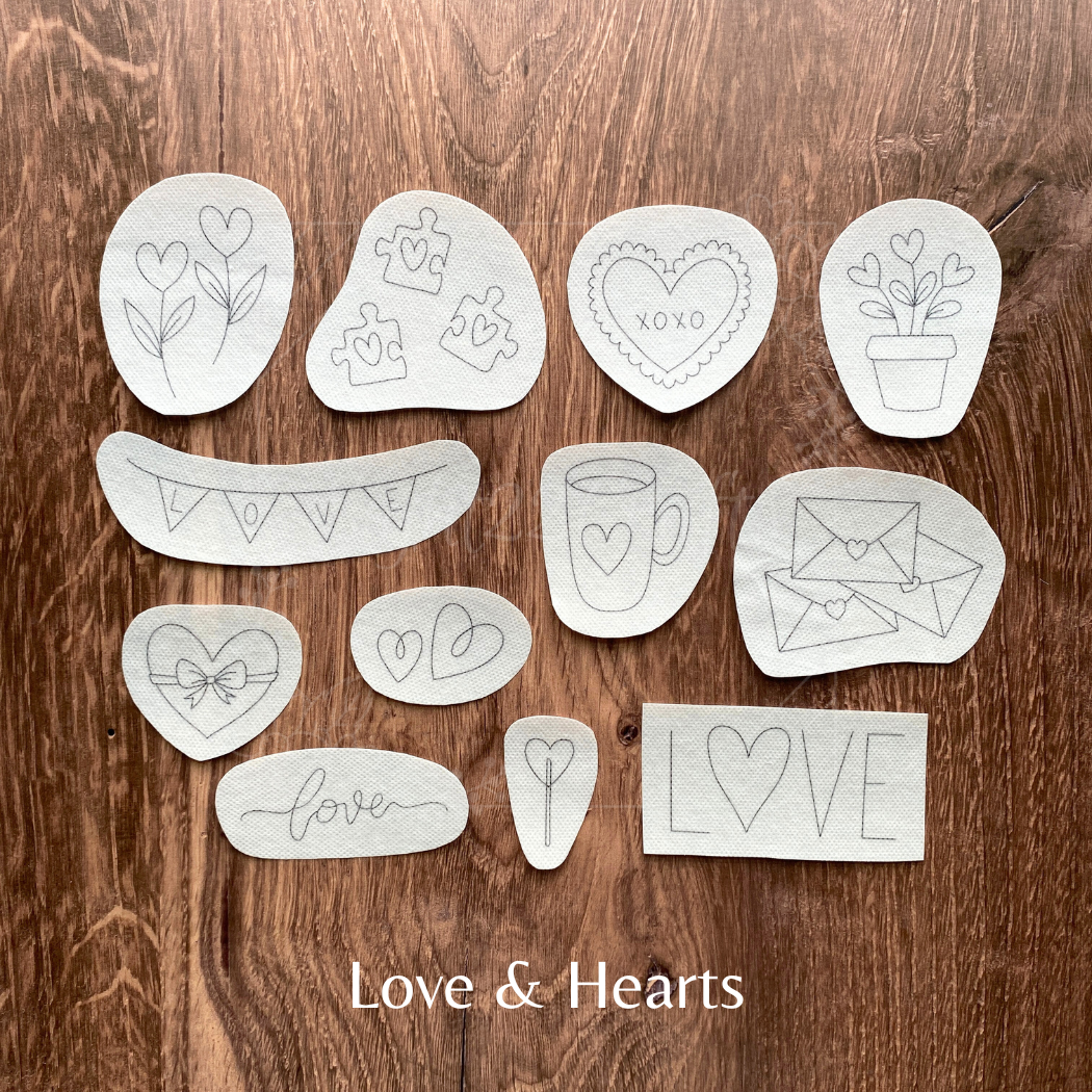 Set of white stencils with various designs on a wooden surface, labeled 'Love & Hearts'.