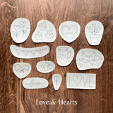 Set of white stencils with various designs on a wooden surface, labeled 'Love & Hearts'.