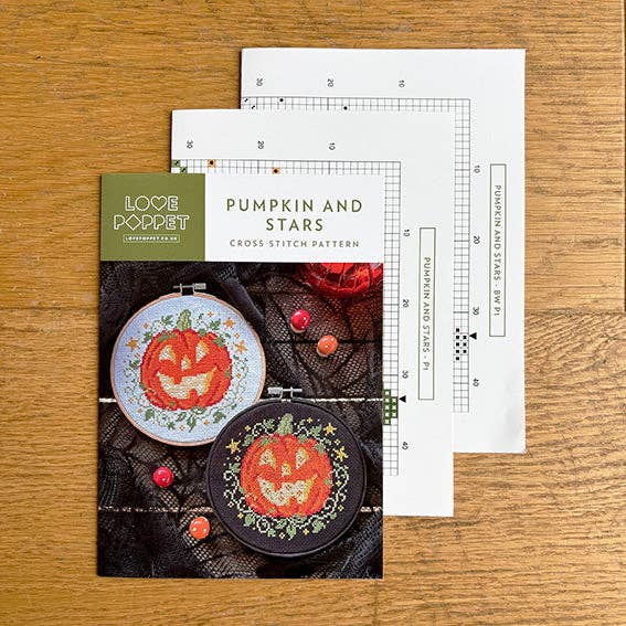 Cross stitch kit with pattern, hoop, and ruler on a wooden surface