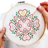 Embroidery hoop with a colorful heart and butterfly design on white fabric.
