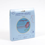 Embroidery kit packaging with a floral design on a light blue background
