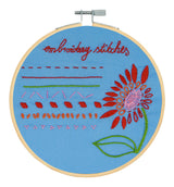 Embroidery hoop with floral design and text on a blue background