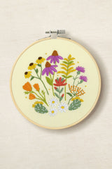 Embroidery hoop with colorful floral design on a beige background