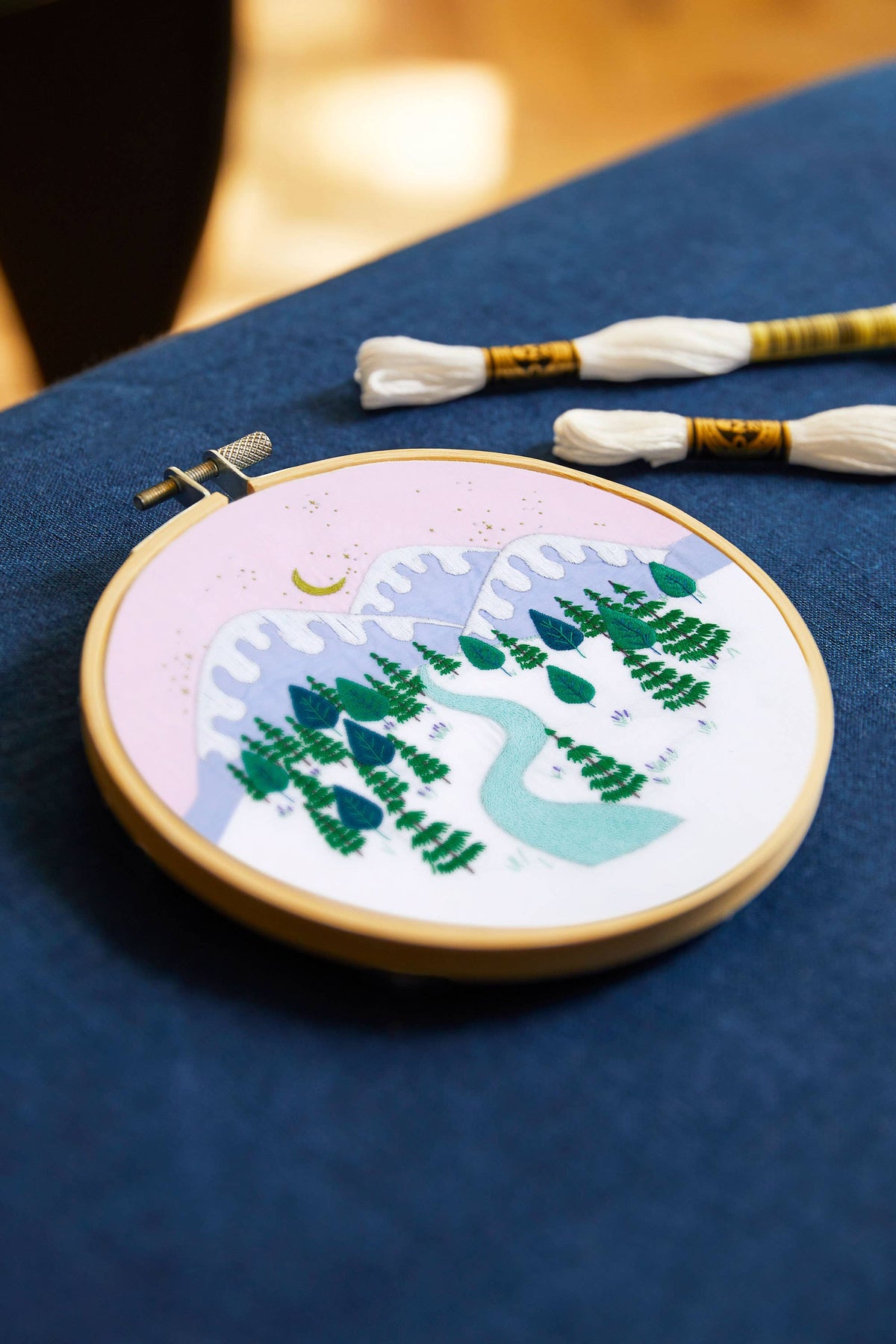 Embroidery hoop with a nature-themed design on a blue fabric background