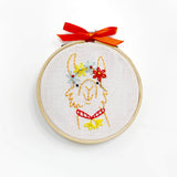 Embroidery hoop with a llama design and red bow on a white background