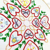 Embroidery design with hearts, bees, and dragonflies on a white background