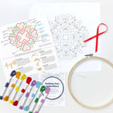 Embroidery kit with patterns, threads, and an embroidery hoop on a white background