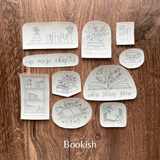 Set of book-themed coasters on a wooden surface with 'Bookish' branding.