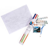 Paint by numbers kit with paint tubes, a canvas, and brushes on a white background