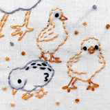 Embroidered design of three chicks on fabric with seeds.