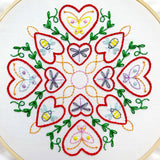 Embroidery hoop with a colorful heart and butterfly pattern on white fabric.