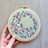 Embroidery hoop with birds and flowers on a textured surface