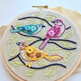 Embroidery hoop with colorful birds and leaves on a light background