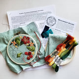 Embroidery kit with floral design, threads, and instructions on a light surface