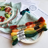 Embroidery hoop with colorful thread skeins and a partially completed floral embroidery design.
