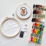 Embroidery kit with hoop, threads, and completed hedgehog design on a white background