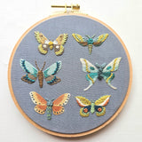 Embroidery hoop with embroidered butterflies on a gray fabric background