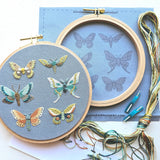 Embroidery hoop with embroidered butterflies and embroidery thread on a blue background
