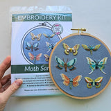 Embroidery kit with embroidered moths and packaging on a white background