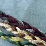 Braided yarn in various colors on a textured fabric background