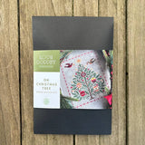 Cross stitch kit packaging with 'Love Poppet' branding on a wooden surface