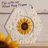 Hexagonal fabric piece with embroidered sunflower design on a wooden surface
