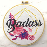 Cross-stitched hoop with 'Badass' and floral design on a white background