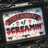Framed cross-stitched artwork with 'Dreamin' of Screamin'' text and Halloween-themed designs.