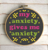 Cross-stitched hoop with colorful text on a wooden background