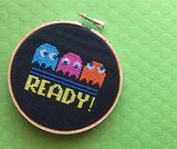 Embroidery hoop with 'READY!' text and colorful characters on a green background