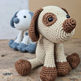 Two crocheted dog toys, one beige and brown, the other blue and white, on a wooden surface.
