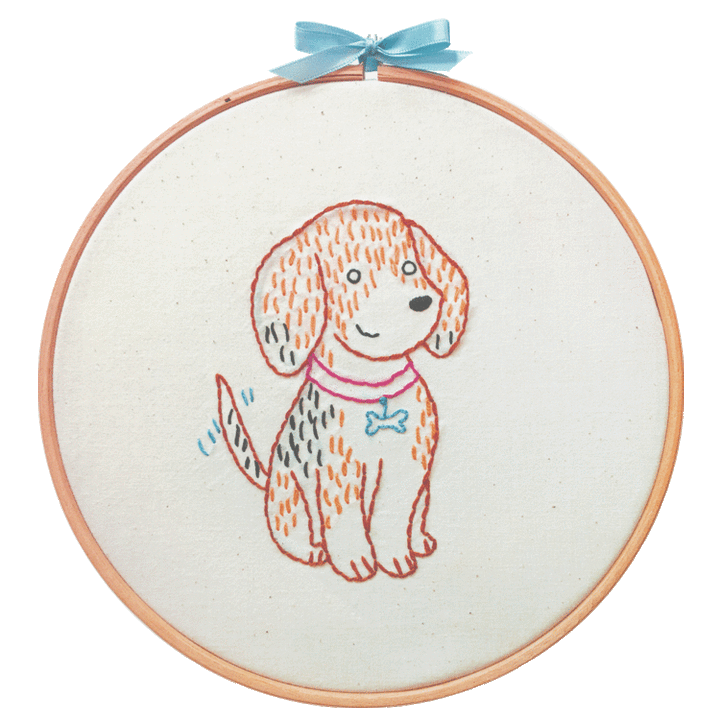 An embroidery hoop with a light blue bow on top with an embroidered puppy on cream colored fabric.
