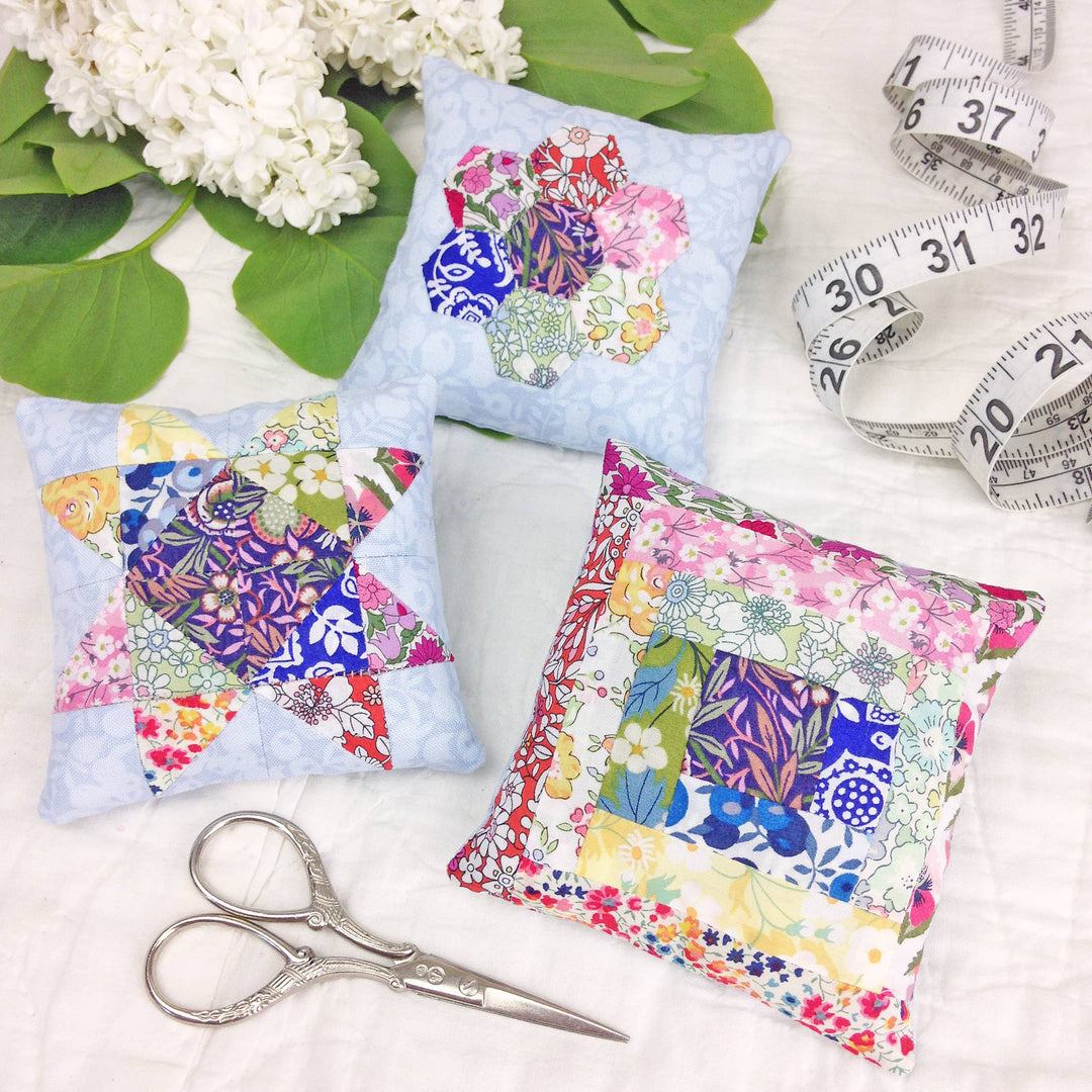 Colorful fabric patches on a white surface with scissors and a measuring tape.