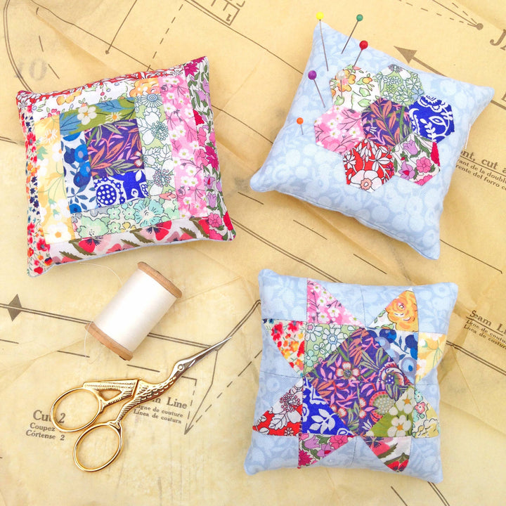 Three colorful fabric patches on a wooden surface with scissors and thread spool.