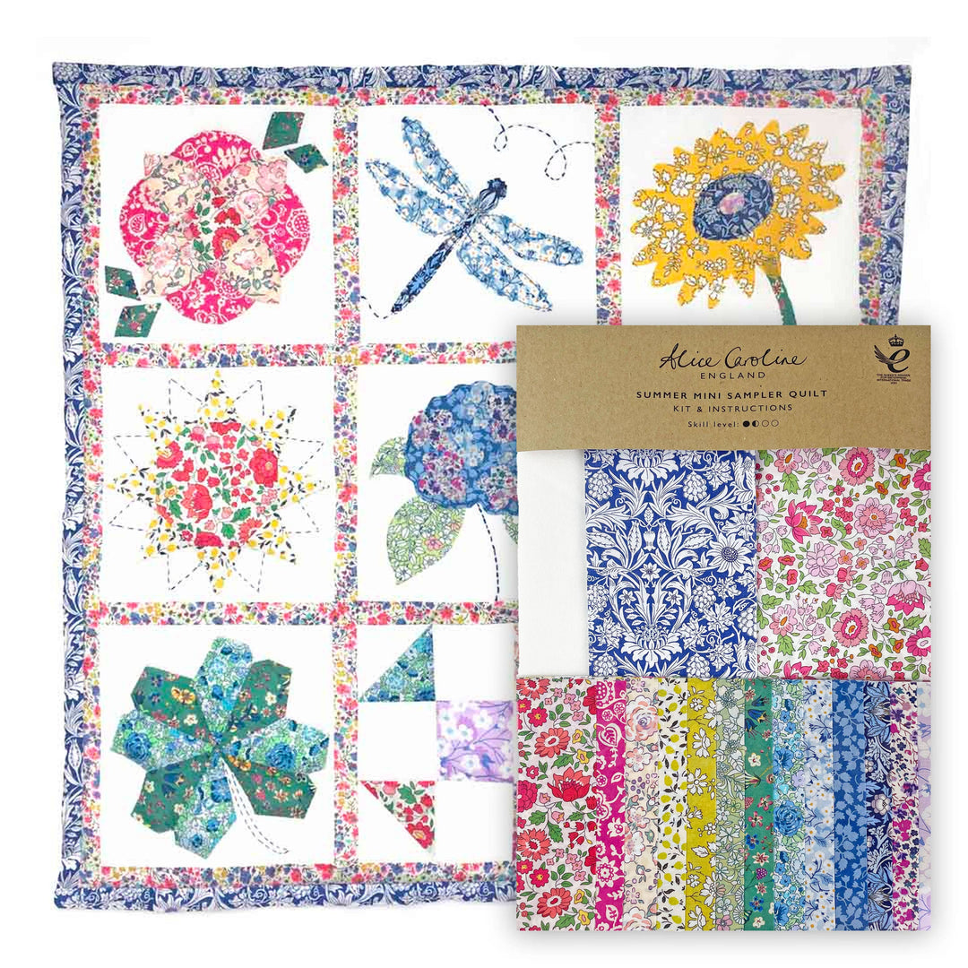 Colorful quilt with floral and nature-themed blocks and a kit packaging on a white background