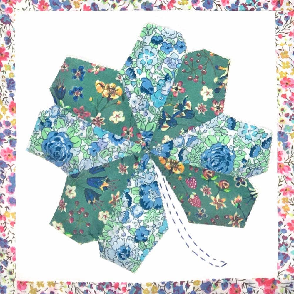 Hexagonal fabric pieces with floral patterns arranged in a circular pattern on a colorful border.