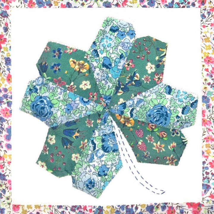 Hexagonal fabric pieces with floral patterns arranged in a circular pattern on a colorful border.