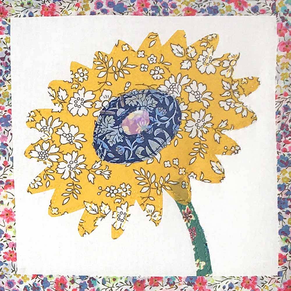 Decorative quilt with a yellow sunflower design on a floral border
