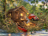 Log cabin by a lake with a red truck and boat, surrounded by trees and nature.